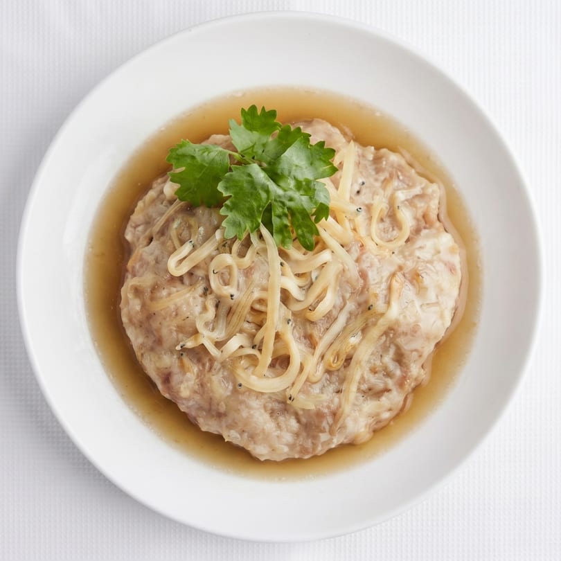 Steamed minced pork with ginger and cilantro in a light broth, served in a white bowl.