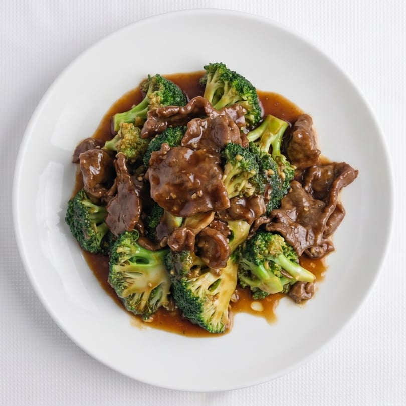 Beef and broccoli stir-fry with a rich brown sauce, served on a white plate.